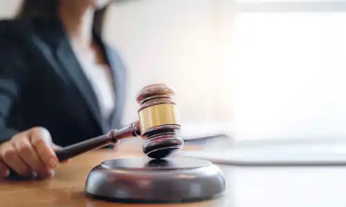 A personal injury lawyer holding a gavel in her hand in a brightly lit office.