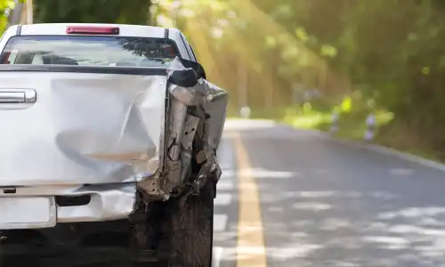 The back of a silver pickup truck stuck on the side of a road after an accident.