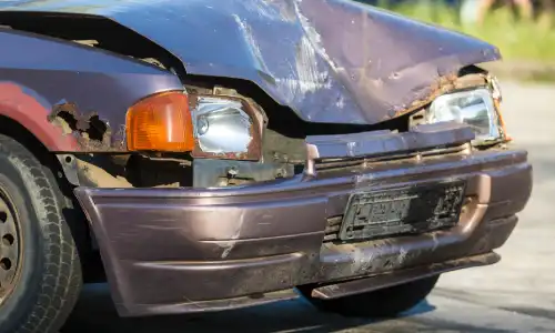 The damaged front end of a purple car that got into an accident with another vehicle