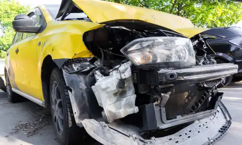 An accident victim's yellow vehicle parked and waiting for repairs after a crash.