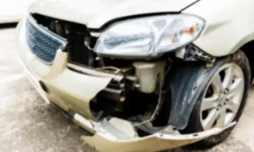 A semi-focused shot of a damaged front end of an accident victim's car.