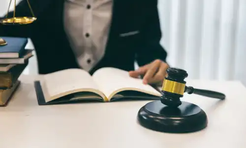 A lawyer seated at a desk with one hand on an open book as he prepares for a case.