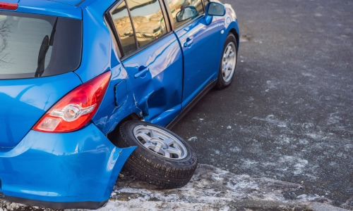 A blue vehicle with a wheel fallen off after an accident on the road.